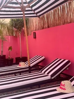 a group of benches in front of a pink wall at Riad Looma in Marrakech