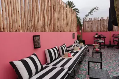 a row of benches against a pink wall at Riad Looma in Marrakech