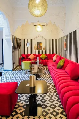 a living room with a red couch and tables at Riad Looma in Marrakech