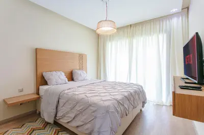 a bedroom with a large bed and a television at Bel appartement vue sur piscine, fibre optique, parking gratuit in Marrakech
