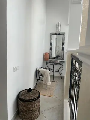 a hallway with a chair and a table with a mirror at Riad zouina in Marrakech