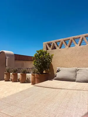 a bed sitting on a patio with potted plants at Momo House- Riad Zaza in Marrakech