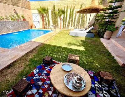 a table and chairs in a yard next to a pool at Villa El Ilham réservée aux familles in Marrakech