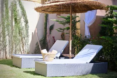 two lounge chairs and an umbrella in a yard at Villa El Ilham réservée aux familles in Marrakech