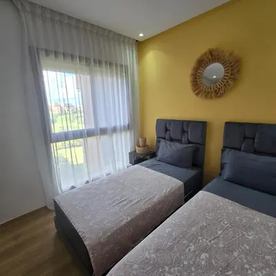 a bedroom with two beds and a mirror and a window at Luxury Flat 2 Bedrooms Prestigia Golf City in Marrakech