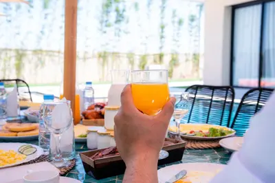a person holding up a glass of orange juice at Modern Villa Selma in Marrakech