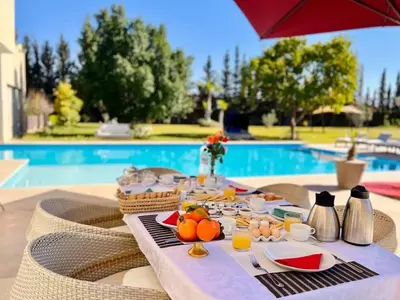 a table with food and fruit on it next to a pool at Spacious Villa with Mountain Views - 550 m² in Marrakech