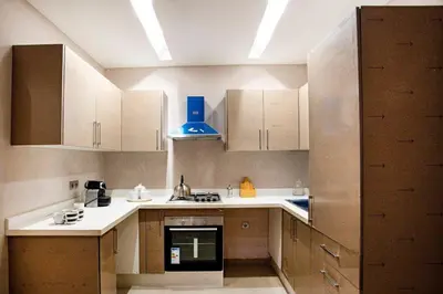 a small kitchen with white cabinets and a blue light at Charming duplex appartment in Marrakech