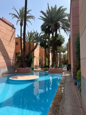 a swimming pool with palm trees in a building at Comfortable house with pool in Marrakech