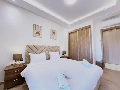a bedroom with a large white bed and a wooden dresser at Modernes Apartment in Top-Lage in Guéliz Marrakech in Marrakech
