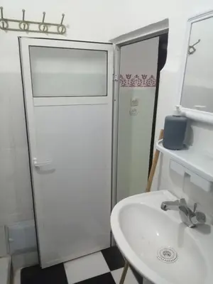 a white bathroom with a sink and a shower at Apartment 3 mins Place jamaa el fana in Marrakech