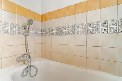 a bath tub with a shower in a tiled bathroom at Design Elegant Appartement in Marrakech
