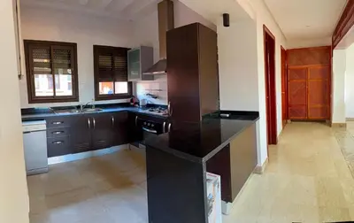 a kitchen with brown cabinets and a black refrigerator at appartement bel vue sur l'atlas in Marrakech