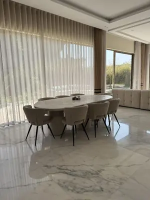 a dining table and chairs in a room with windows at Villa Maymouna in Marrakech