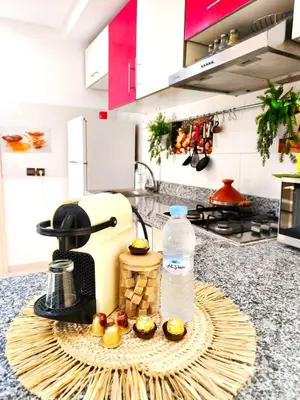 a kitchen counter with a plate of cupcakes and a bottle of water at Appartement cosy Marrakech in Marrakech