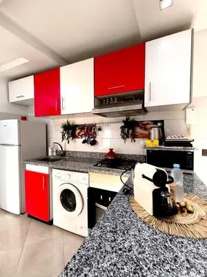 a kitchen with red and white cabinets and a washer at Appartement cosy Marrakech in Marrakech