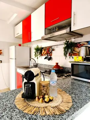 a kitchen counter with a coffee maker and fruit on a table at Appartement cosy Marrakech in Marrakech
