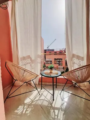 a balcony with a table and two chairs and a window at Appartement cosy Marrakech in Marrakech