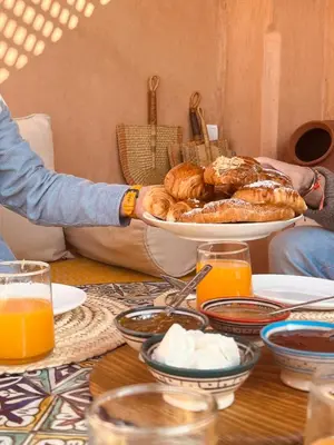 a person holding a plate of pastries on a table at Momo House- Riad Momo in Marrakech