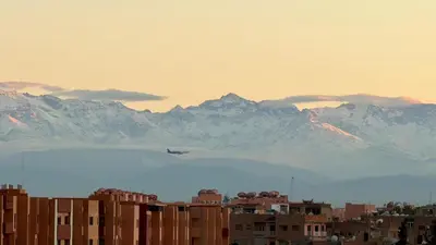 an airplane flying over a city with mountains in the background at Appartement Cosy Majorelle au Centre-Ville - Netflix-Fibre in Marrakech