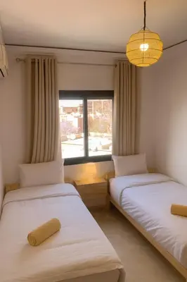 two beds in a room with a window at Appartement Cosy Majorelle au Centre-Ville - Netflix-Fibre in Marrakech
