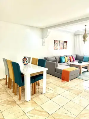 a living room with a couch and a table and chairs at GHIZLAN Apartment in Marrakech