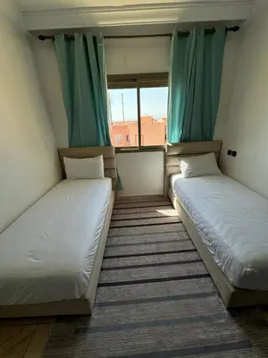 two beds in a room with a window at GHIZLAN Apartment in Marrakech