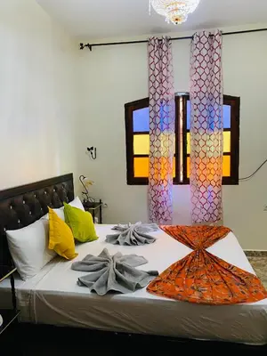 a bedroom with a bed with an orange blanket on it at Dar béa in Marrakech