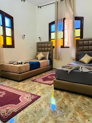 two beds in a room with windows and rugs at Dar béa in Marrakech