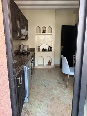 a kitchen with a counter and a table and a chair at Appartement PREMIUM VILLAGE in Marrakech