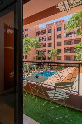 a patio with a table and chairs on a balcony at Charment et spacieux 2 chambres avec salon in Marrakech