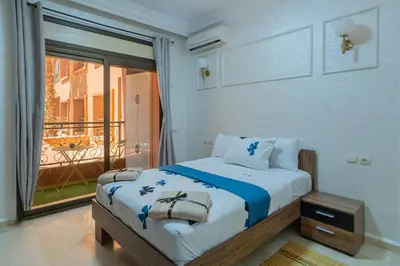 a bedroom with a bed with a view of a balcony at Charment et spacieux 2 chambres avec salon in Marrakech