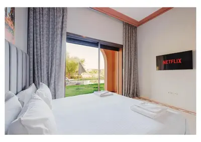 a bedroom with a white bed with a window at Villa Camelia avec Jacuzzi, Cuisinière, Piscine in Marrakech