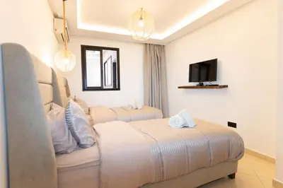 a hotel room with two beds and a tv at Appartement élégant avec jacuzzi à deux pas de Guéliz in Marrakech