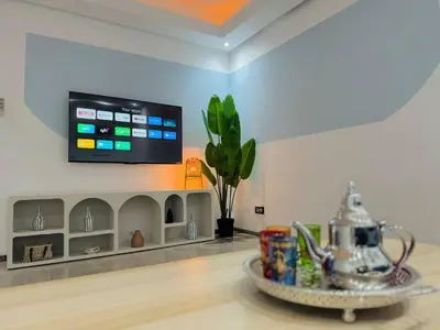 a living room with a tv on the wall and a table at Gueliz Gem Chic, Comfy & Central in Marrakech