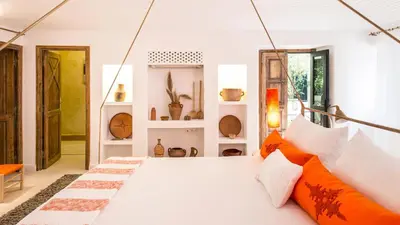 a bedroom with a white bed with orange pillows at Dar-el-adaka in Marrakech