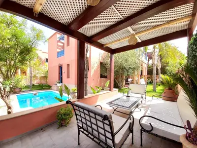 an outdoor patio with a pool and a pergola at CYCAS VILLA TARGA GARDEN -Only Family in Marrakech