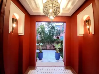 a hallway with orange walls and a chandelier at CYCAS VILLA TARGA GARDEN -Only Family in Marrakech