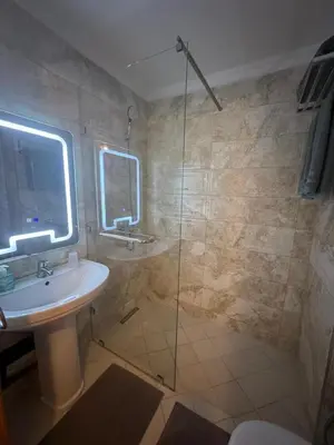 a bathroom with a sink and a glass shower at Sofia Palmeraie Appartement in Marrakech