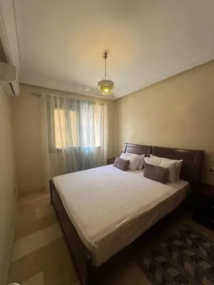 a bedroom with a large white bed with a chandelier at Sofia Palmeraie Appartement in Marrakech