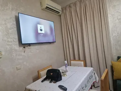 a room with a table and a tv on the wall at appartement mabrouka in Marrakech