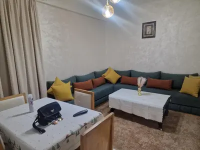 a living room with a blue couch and two tables at appartement mabrouka in Marrakech