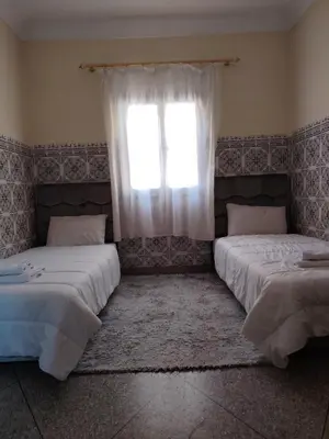 two beds in a room with a window at Maison traditionnelle marocaine à Marrakech in Marrakech