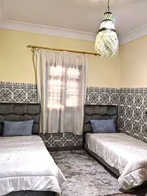 a bedroom with two beds and a window with a chandelier at Maison traditionnelle marocaine à Marrakech in Marrakech