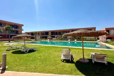 a swimming pool with chairs and umbrellas at Noria Golf Marrakech in Marrakech