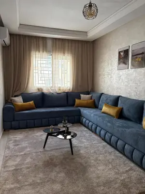 a living room with a blue couch and a table at Charmant appartement familial in Marrakech