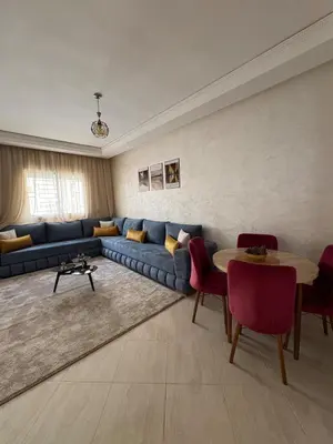 a living room with a blue couch and a table at Charmant appartement familial in Marrakech