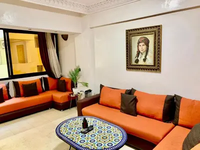 a living room with orange furniture and a painting on the wall at Appartement Miramas 2 E2 in Marrakech