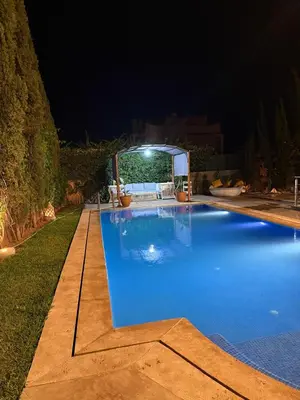 a large blue swimming pool at night at Villa Palmeraie in Dar Caïd Layadi