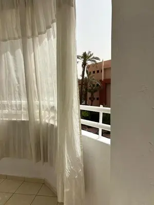 a window with a white curtain on a balcony at Appartement cosy in Marrakech